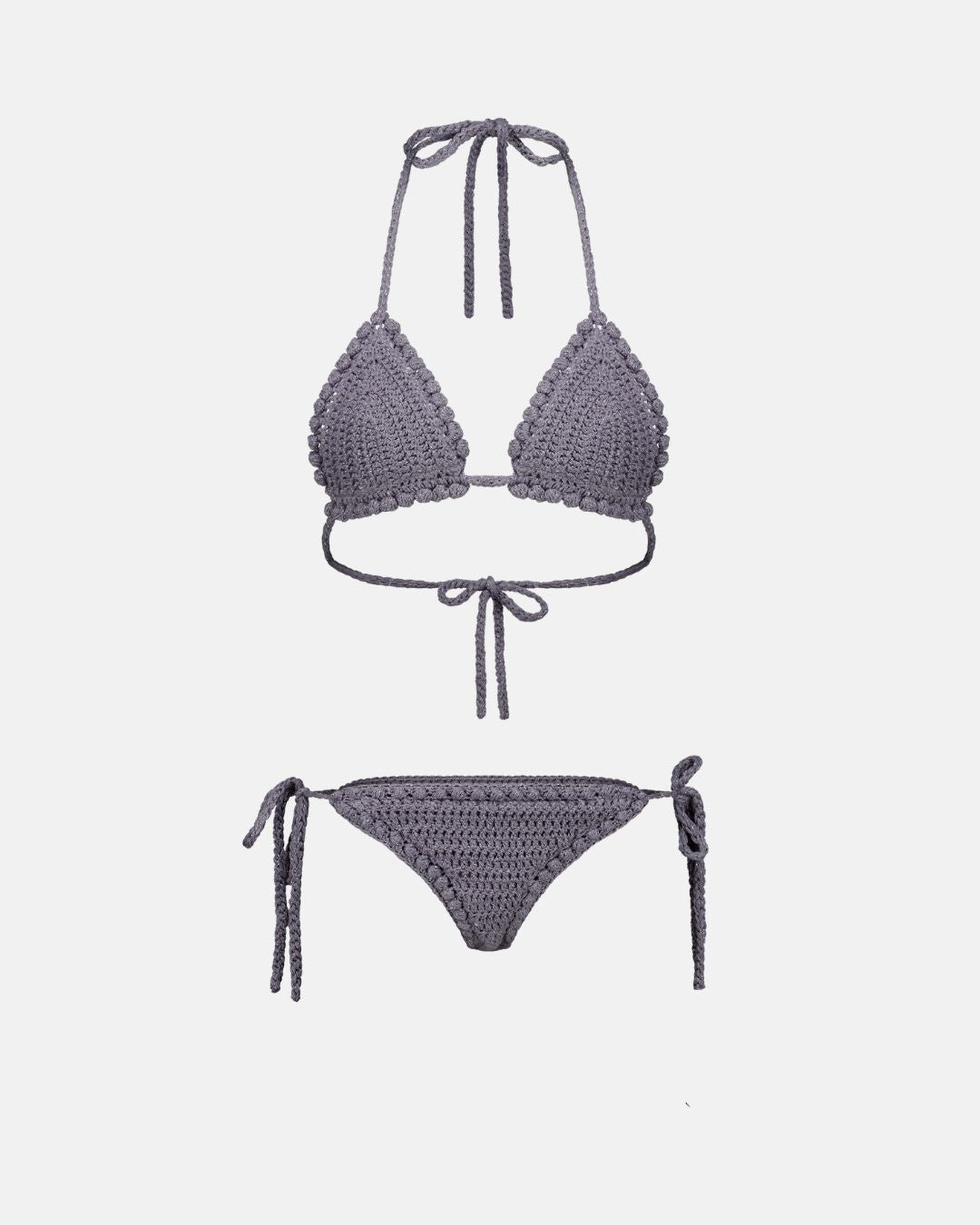 A studio flat lay of the Pompom crochet bikini set in shimmering grey lurex, showing the triangle top and tie-side bottoms with bobble edging.