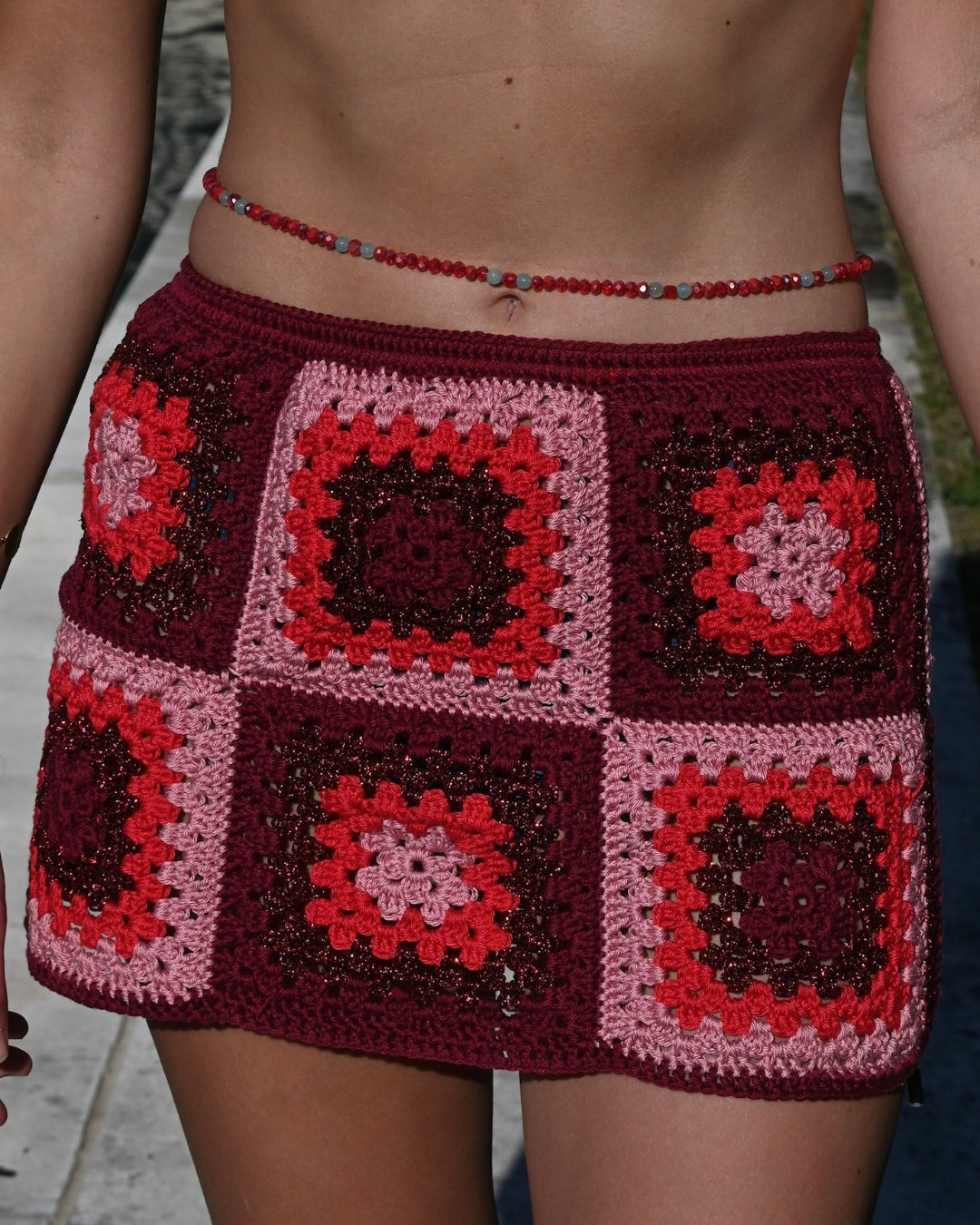Close-up of the Bianca mini skirt's red and pink granny-square crochet, highlighting its intricate handmade texture.