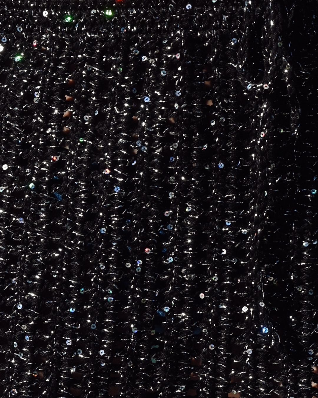 Extreme close-up of the Melissa dress fabric, showing the artisanal hand-crocheted black knit infused with thousands of shimmering silver micro-sequins.