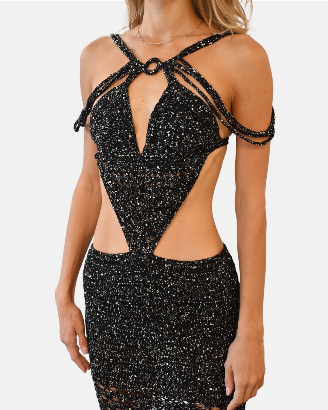 Close-up of the Melissa dress bodice, showing the central ring detail, the plunging neckline, and the multi-strap halter design in sparkling black crochet.